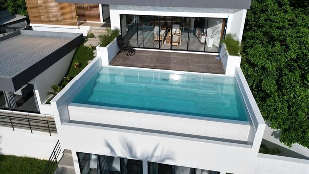 Una casa moderna con piscina en la azotea, ventanas amplias y techo plano.
