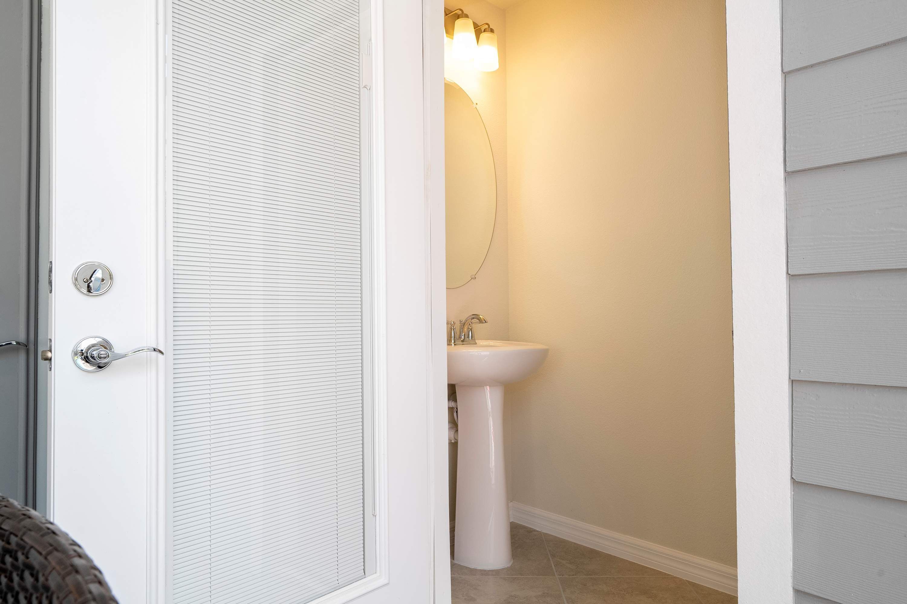 A bathroom with a white door, a sink, and a mirror.