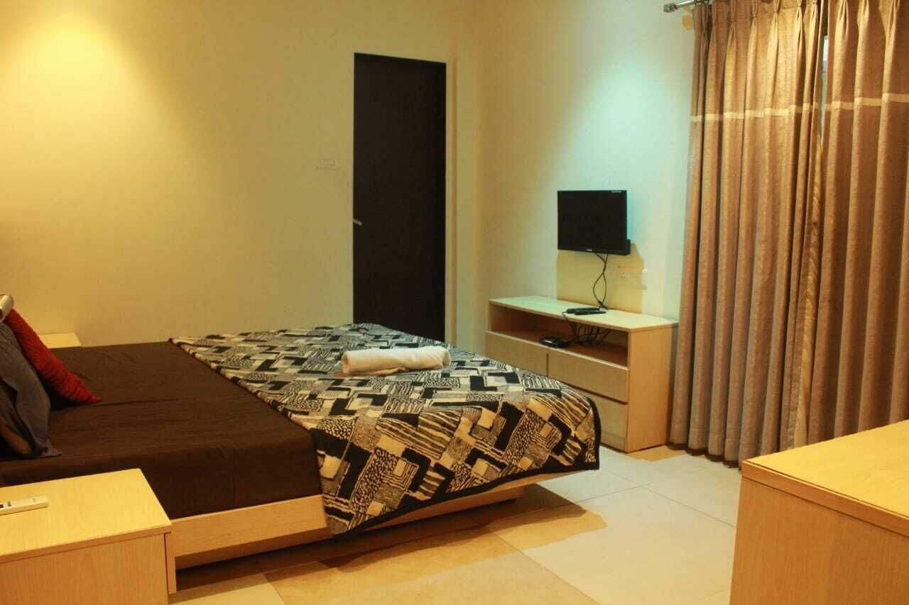 Una camera da letto con un letto, una scrivania, un televisore e una porta.