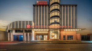 Ein modernes Hilton Garden Inn Hotel mit markanter vertikaler Gestaltung und beleuchteter Beschilderung.