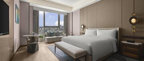 Quarto de hotel moderno com uma cama grande, área de estar, televisão e vista para a cidade.
