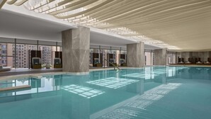 An indoor swimming pool with clear water, large windows, and modern architecture.