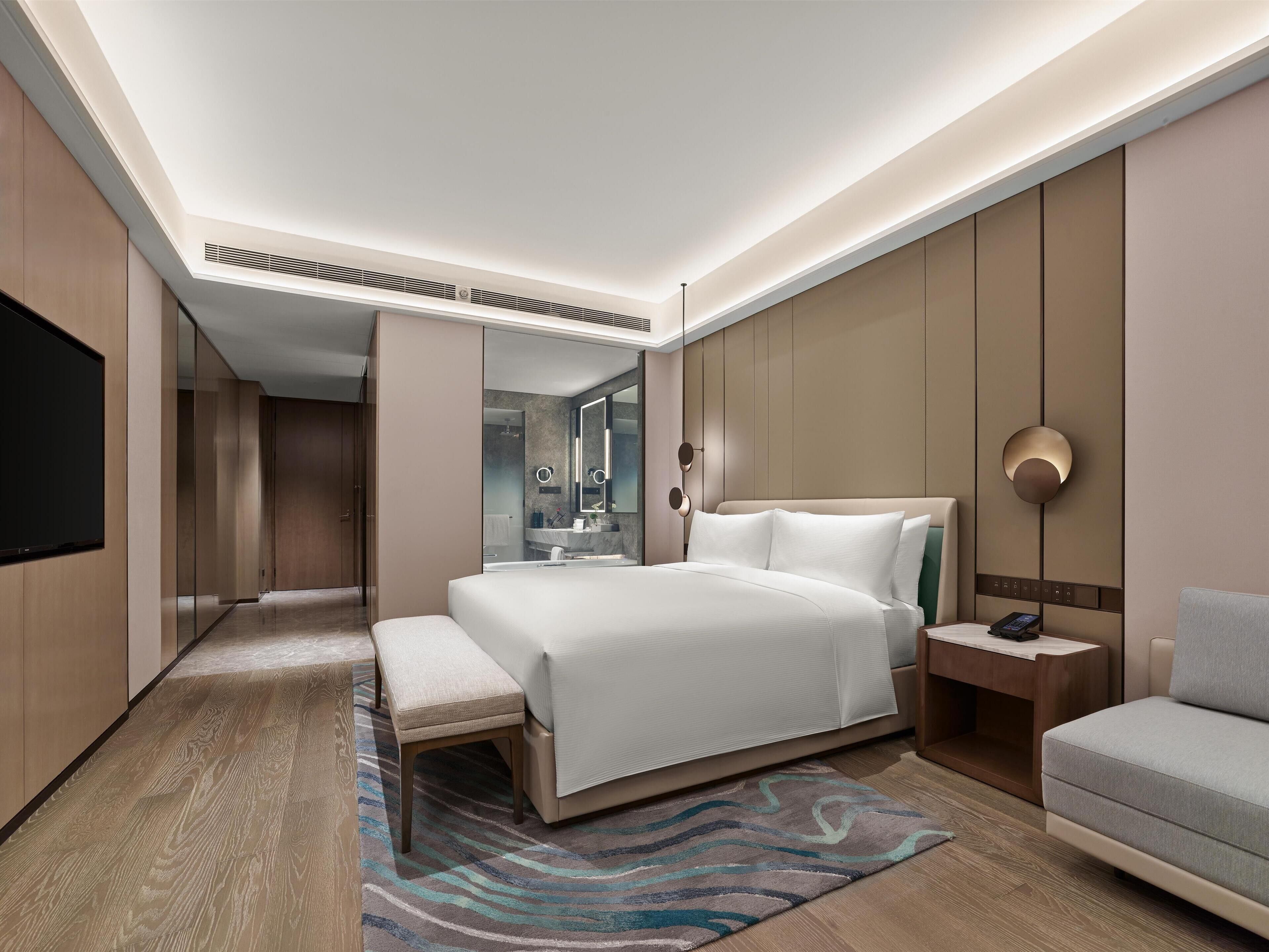 Una habitación de hotel moderna con una cama grande, una mesita de noche y un área de estar.