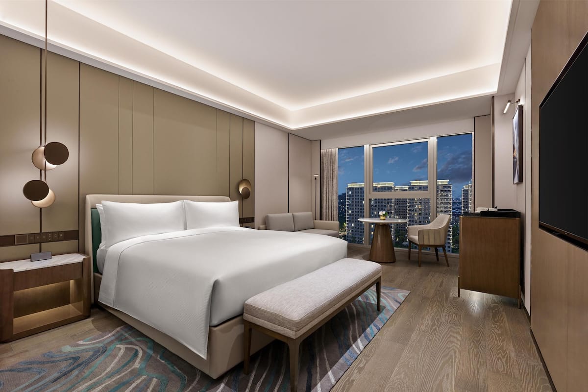 Une chambre d’hôtel moderne équipée d’un grand lit, d’un bureau, d’une chaise, d’une petite table et d’un téléviseur.