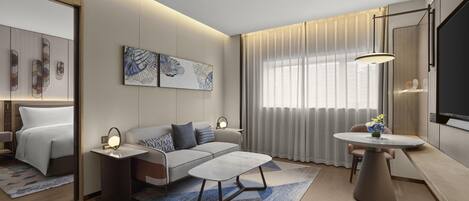 Ein modernes Hotelzimmer mit Bett, Sofa, Esstisch und Bildern an den Wänden.