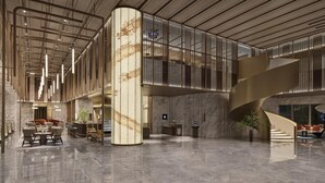 A spacious lobby with a marble floor, a central column, and a staircase.
