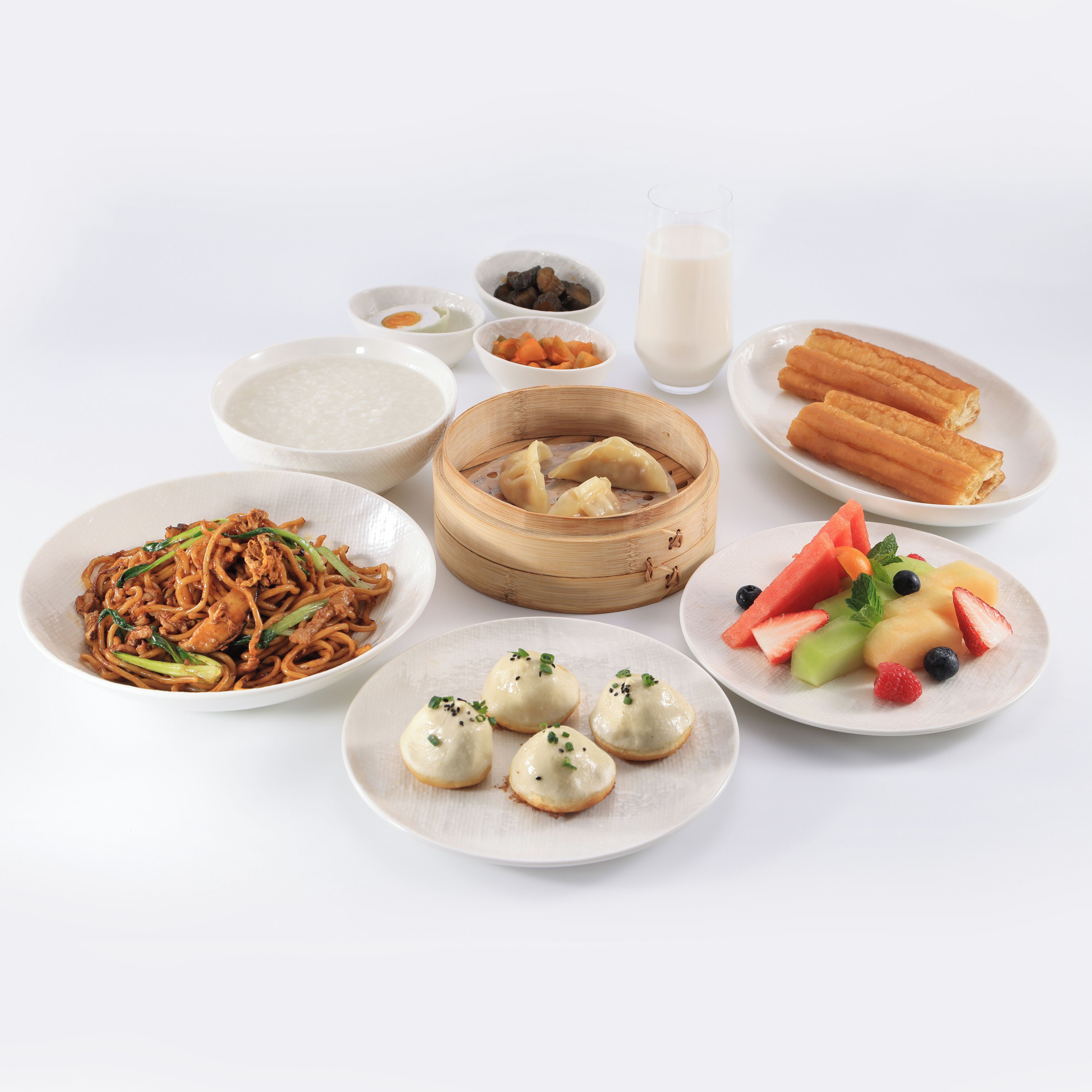 Une variété de plats, notamment des nouilles, des raviolis et des fruits, présentés dans des assiettes.