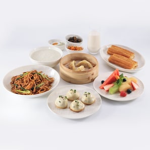Une variété de plats, notamment des nouilles, des raviolis et des fruits, présentés dans des assiettes.