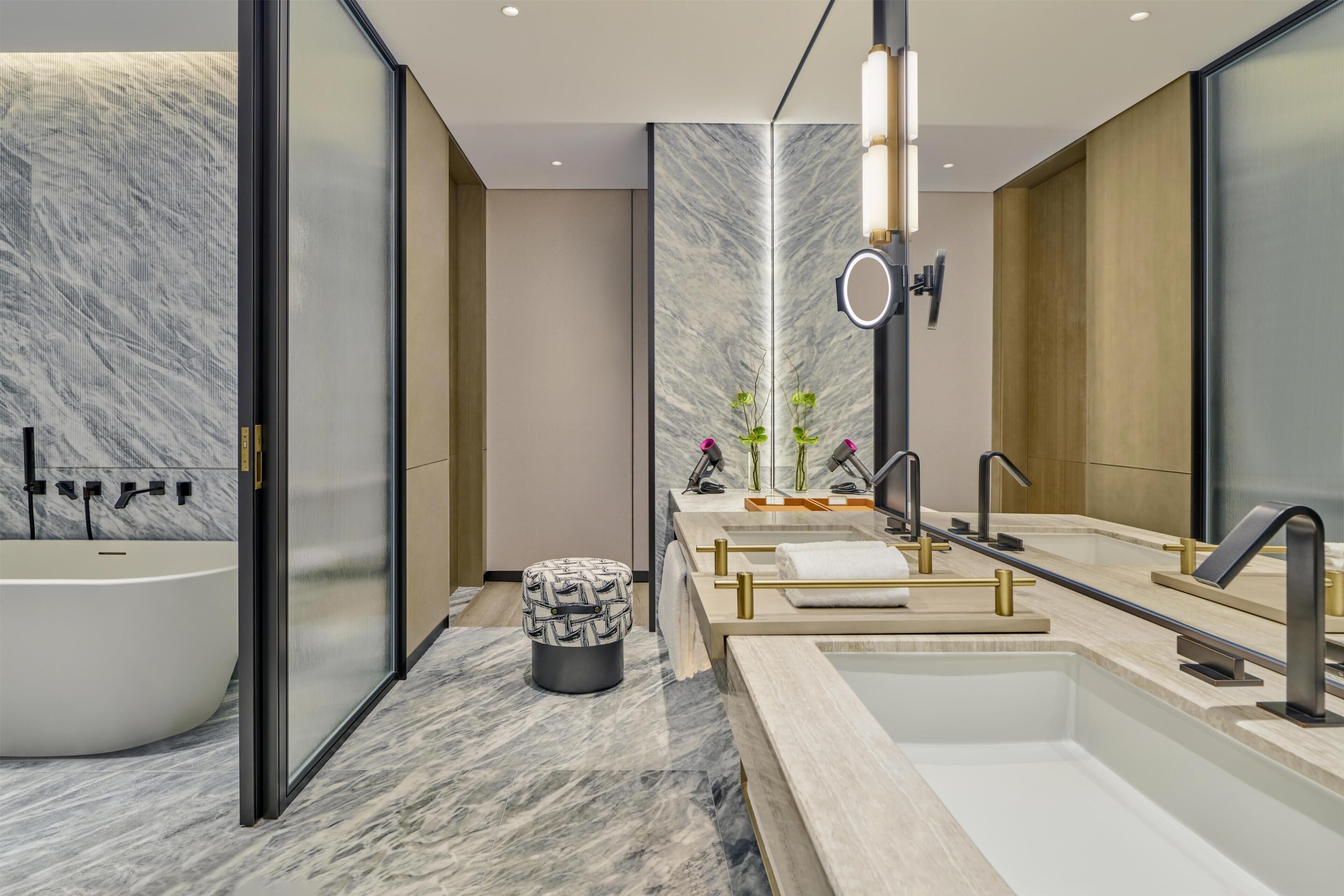 A modern bathroom with a freestanding bathtub, a vanity with a mirror, and a marble floor.