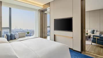A modern hotel room with a large bed, a flat-screen TV, and a city view.