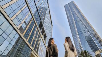 Two people standing in front of tall, modern buildings with reflective glass windows.