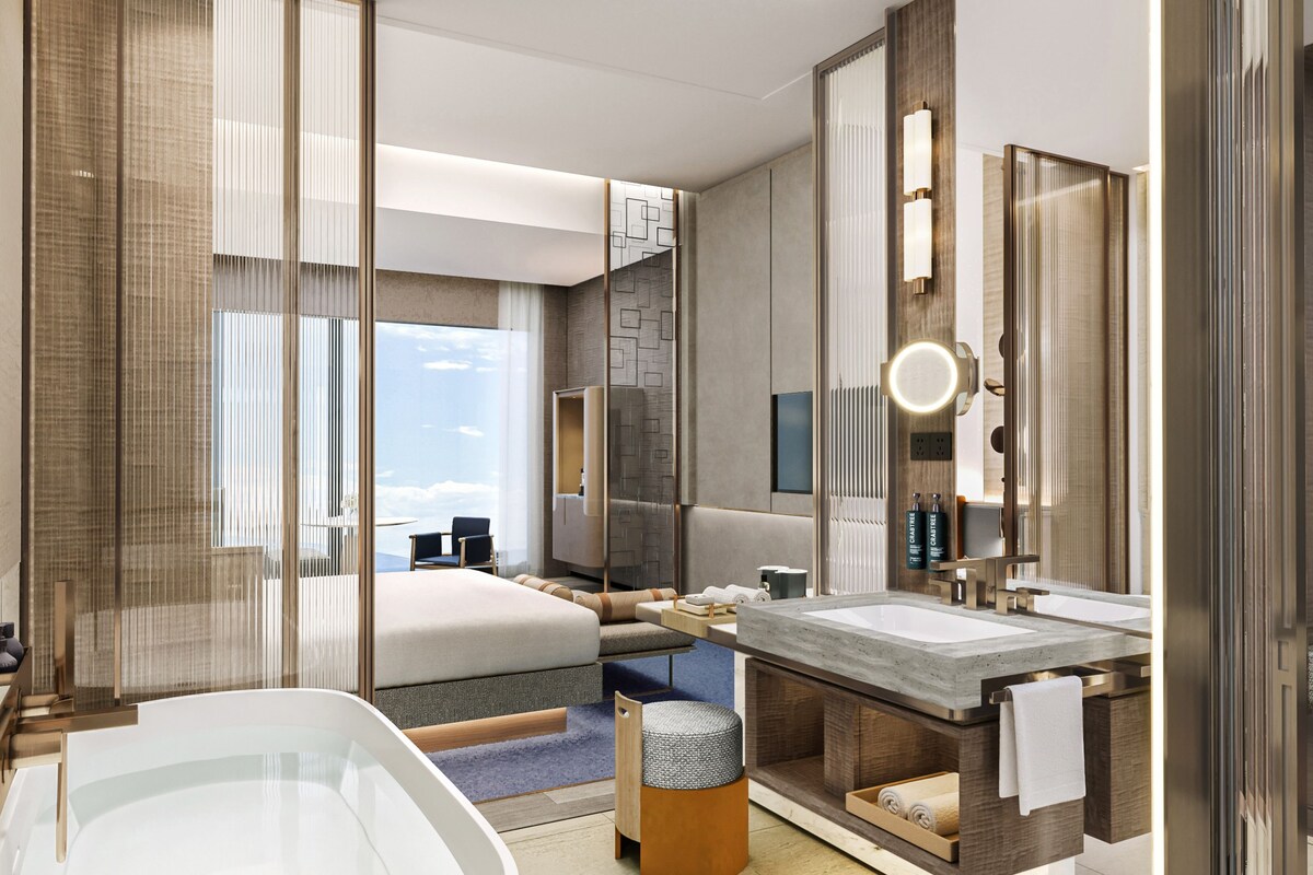Une chambre d’hôtel moderne dotée d’un grand lit, d’une salle de bain avec un lavabo, une baignoire et une vue sur le ciel.