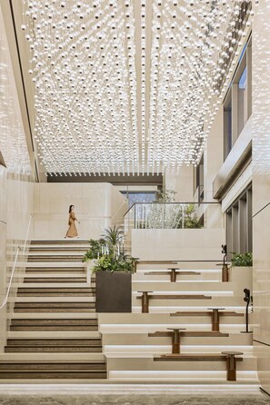 A modern interior with a woman walking up a staircase. - Hilton Shanghai Zhangjiang Science City (Shanghai)