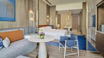 Une chambre d’hôtel moderne, équipée d’un lit, d’un canapé, d’une table ronde et d’une chaise.