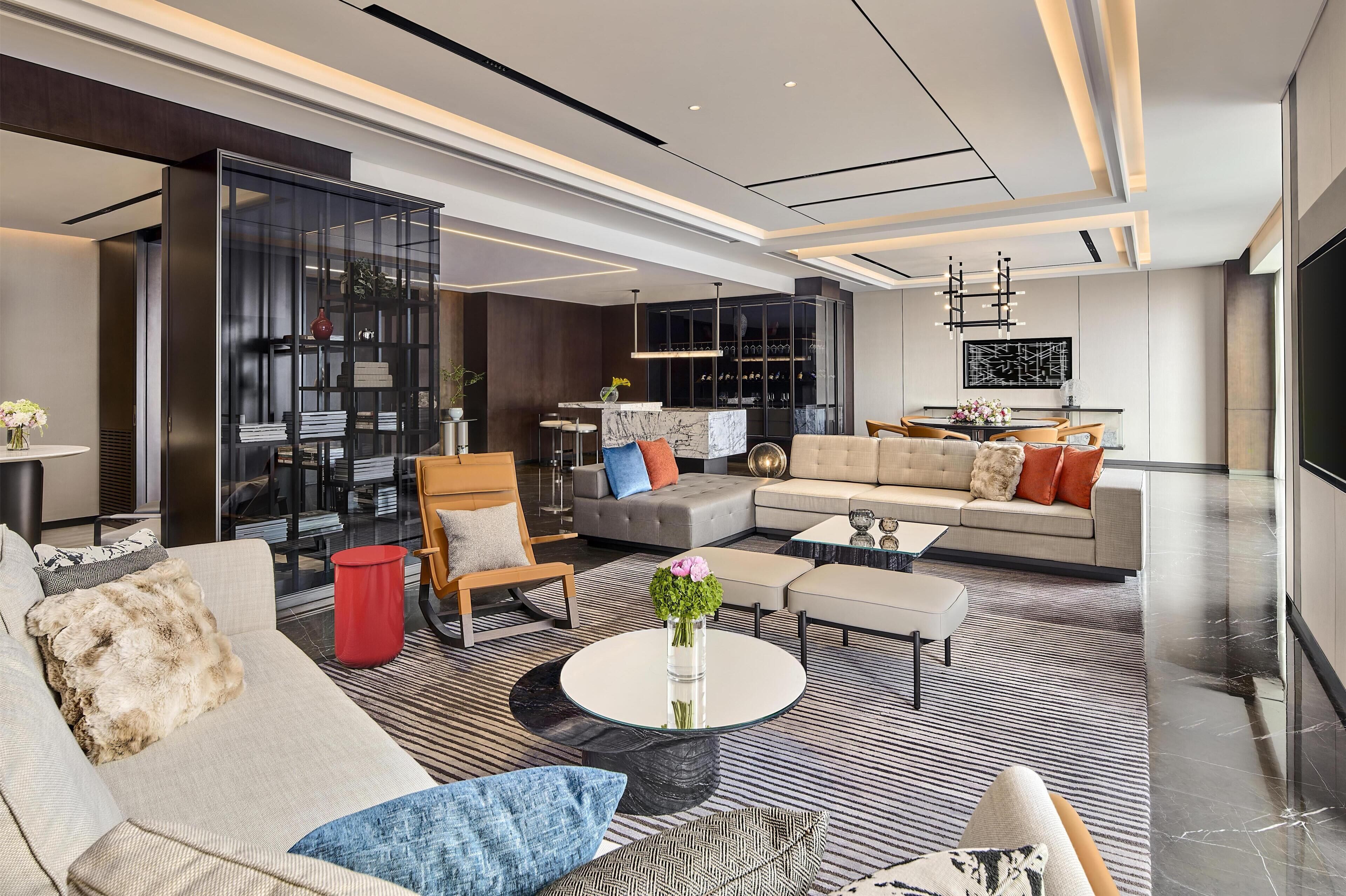 Un salon moderne comprenant un canapé, des fauteuils, une table basse et une bibliothèque.
