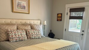 A neatly made bed with a quilted headboard, a bedside lamp, and a framed picture on the wall.