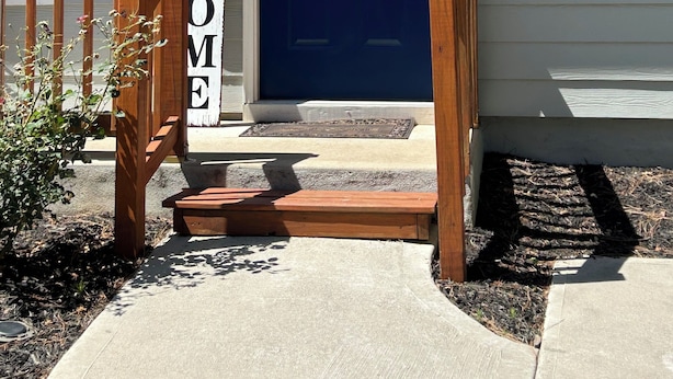 A house with a blue front door, a wooden front porch, and a welcome sign.