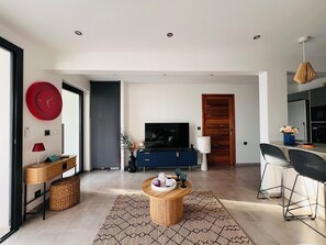Relax in this stylish living space with a large flat-screen TV, comfortable seating, and a clean, uncluttered layout.