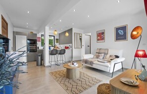 Relax in a stylish living space with a central seating area, dining table, and fully equipped kitchen.