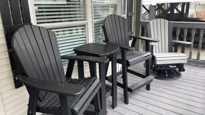Una terraza de madera con sillas Adirondack y una pequeña mesa.