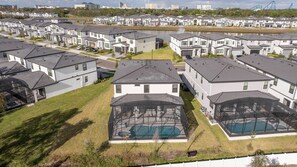 Un quartier résidentiel avec des maisons modernes, une piscine et un lac en arrière-plan.