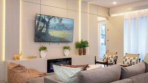 Ein modernes Wohnzimmer mit flachbildfernseher, Sofa, Couchtisch und Kamin.