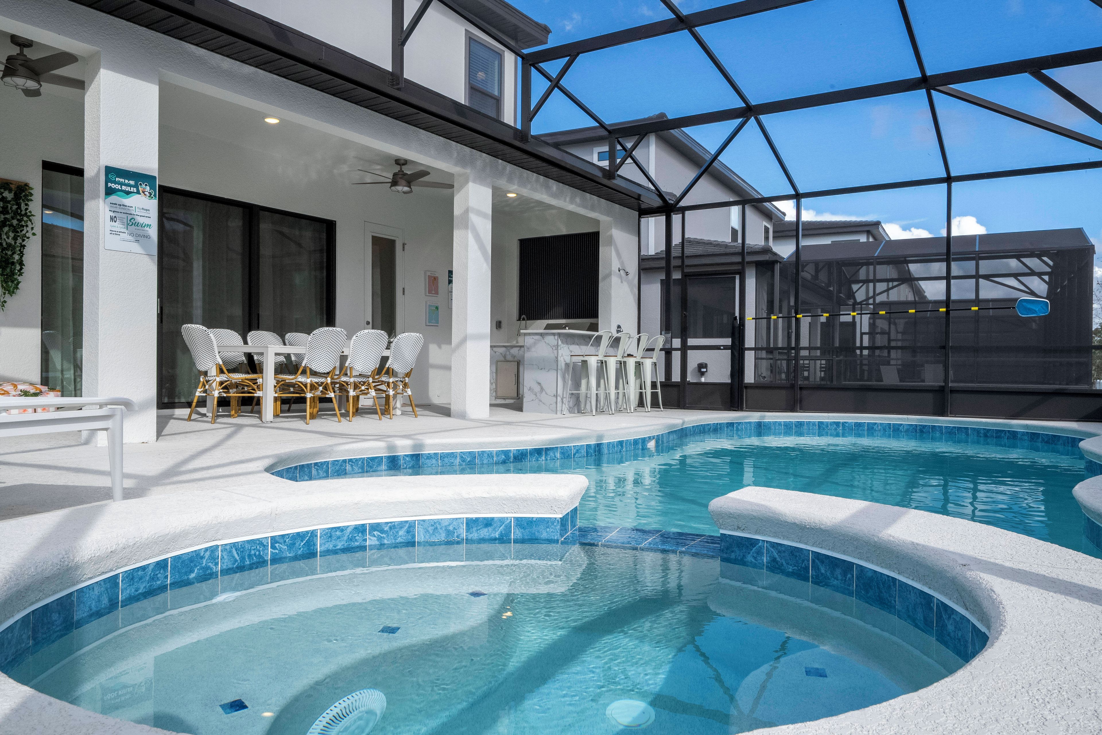 An indoor swimming pool with clear blue water, surrounded by white walls and a glass enclosure.