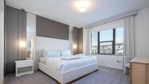 Ein modernes Hotelzimmer mit einem großen Bett, Nachttischen, einem Spiegel und einem Fenster mit Blick auf die Stadt.