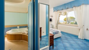 A bedroom with a large window, a bed, a nightstand, and a bathroom with a bathtub and a mirror. - Villa Ambra by My Villa Collection (Casamicciola Terme)