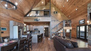 A spacious kitchen with modern appliances, a dining area with a wooden table and chairs, and a cozy living area with a leather sofa and a fireplace.