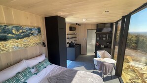 Een moderne slaapkamer met een groot bed, een zithoekje en uitzicht op het groen.