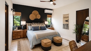 Een slaapkamer met een bed, nachtkastjes, een plafondventilator en een groot raam.