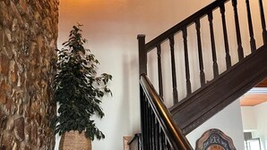 A wooden staircase with a textured wall and a wall-mounted clock. - Casa Rural Selmo (Carreno)