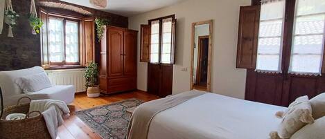 A bedroom with two beds, a wooden wardrobe, a potted plant, and a hanging light fixture.