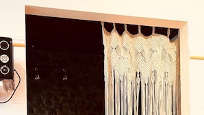 A doorway with a macramé curtain, a wooden chair, and a tiled floor. - Casa Rural Selmo (Carreno)