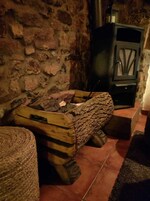 Un muro de piedra rústica, un hogar de troncos y un armario negro con puerta de cristal.