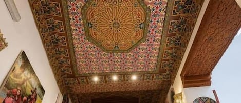 A staircase with a wooden railing, a patterned ceiling, and a wall with a decorative tile border.