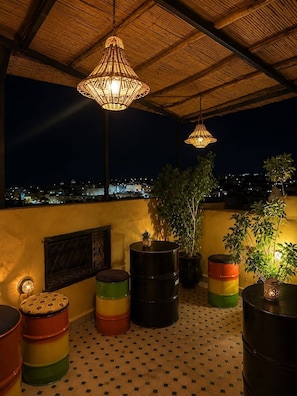 A rooftop terrace with hanging lamps, potted plants, and colorful barrels. - Riad hamad (Fes)