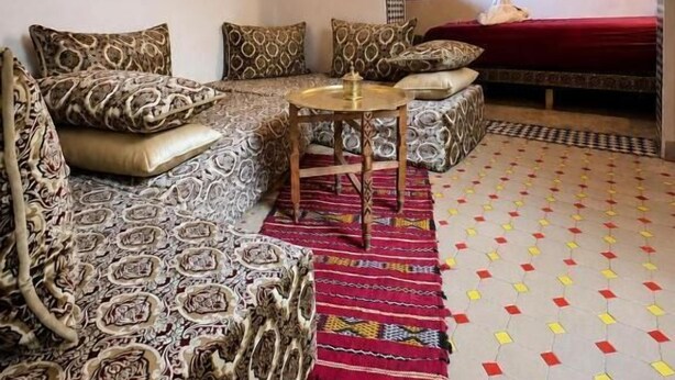 Una habitación con un sofá estampado, una mesita redonda y un tapete con diseño.