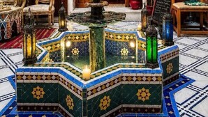 Un vestíbulo con una fuente, puertas de madera y un letrero que dice 'Maymouna'.