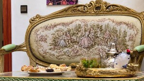 Un sofá tradicional marroquí con diseños intrincados y una mesa colorida y ricamente decorada al frente.