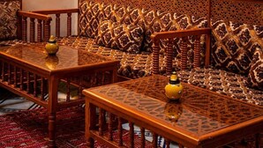 Un interior tradicional con un conjunto de sofá, mesas de madera y una alfombra estampada.