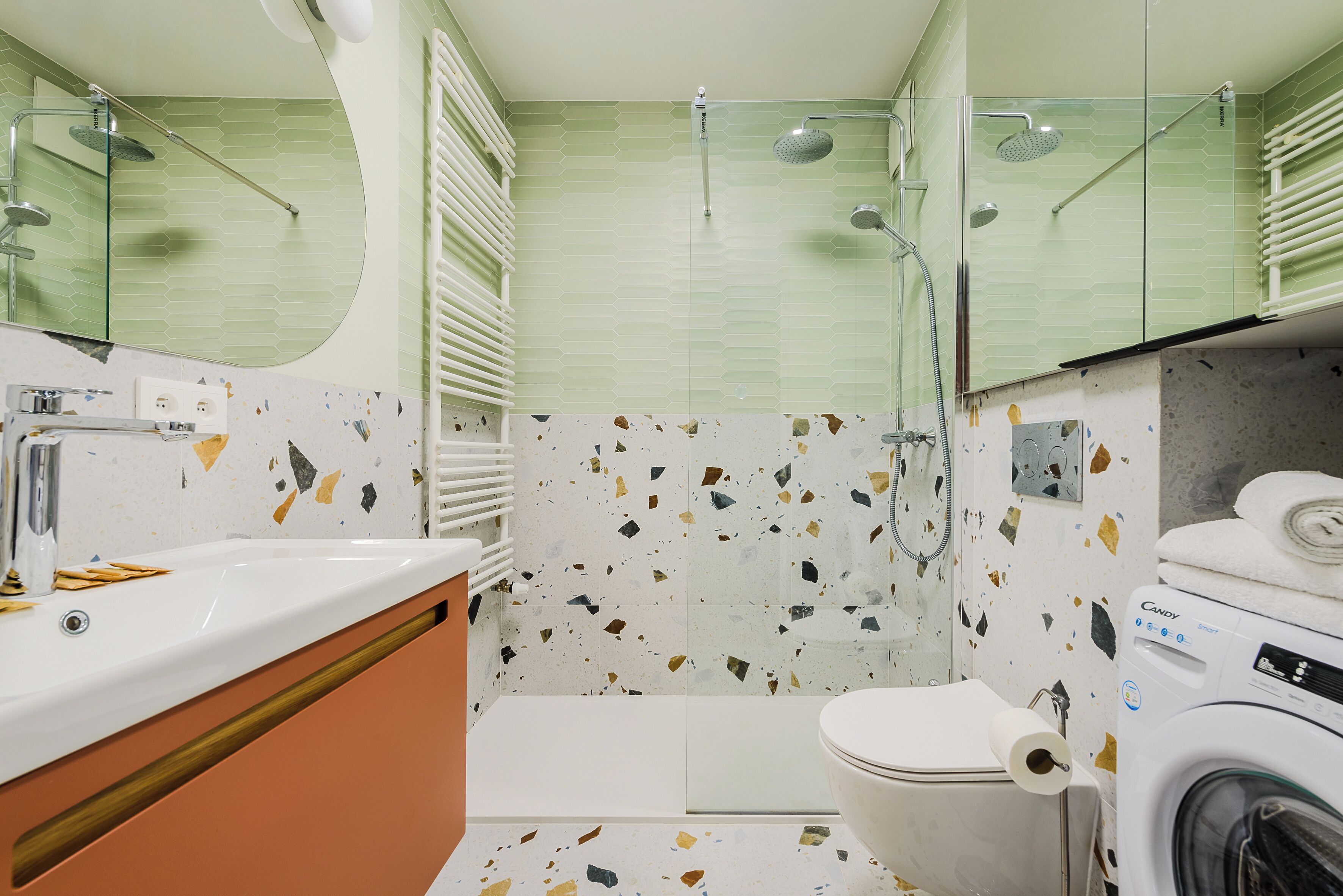 A bathroom with a shower, toilet, sink, and a washing machine.