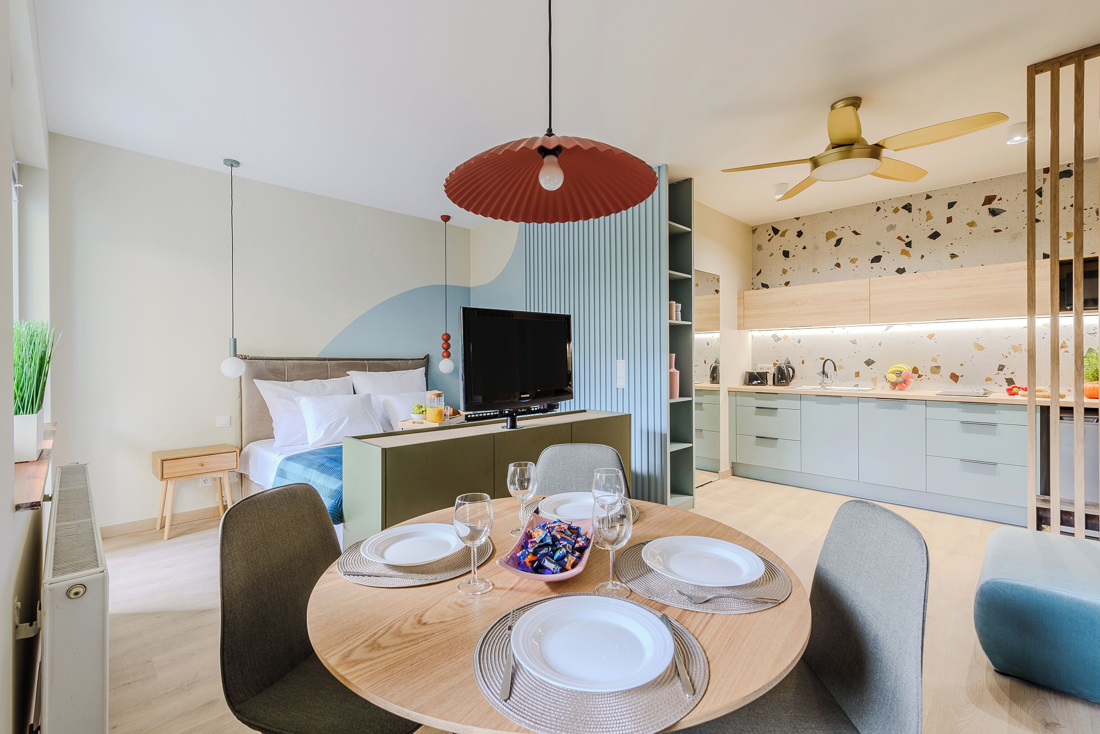 Een moderne hotelkamer met een zithoek, een bed, een televisie en een kitchenette.