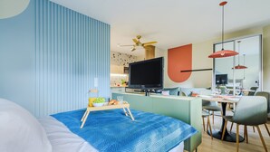 Quarto de hotel moderno com cama, secretária e área de refeições.