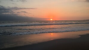 Una playa al atardecer, con olas suaves besando la orilla.