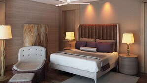 Una habitación de hotel moderna con una cama grande, una silla, dos mesitas de noche y un ventilador de techo.
