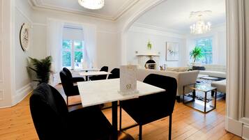 A dining area with a white table and black chairs, a chandelier, and a fireplace with a mantel.