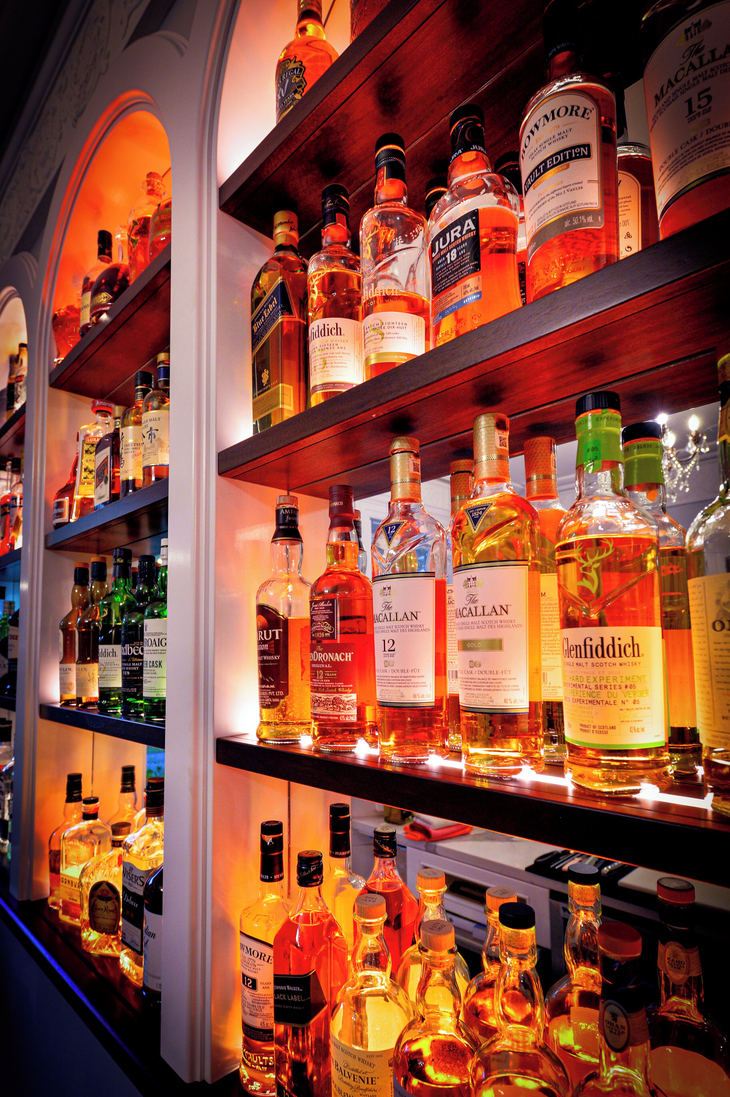 Estantes llenos de diferentes botellas de licor en un bar.