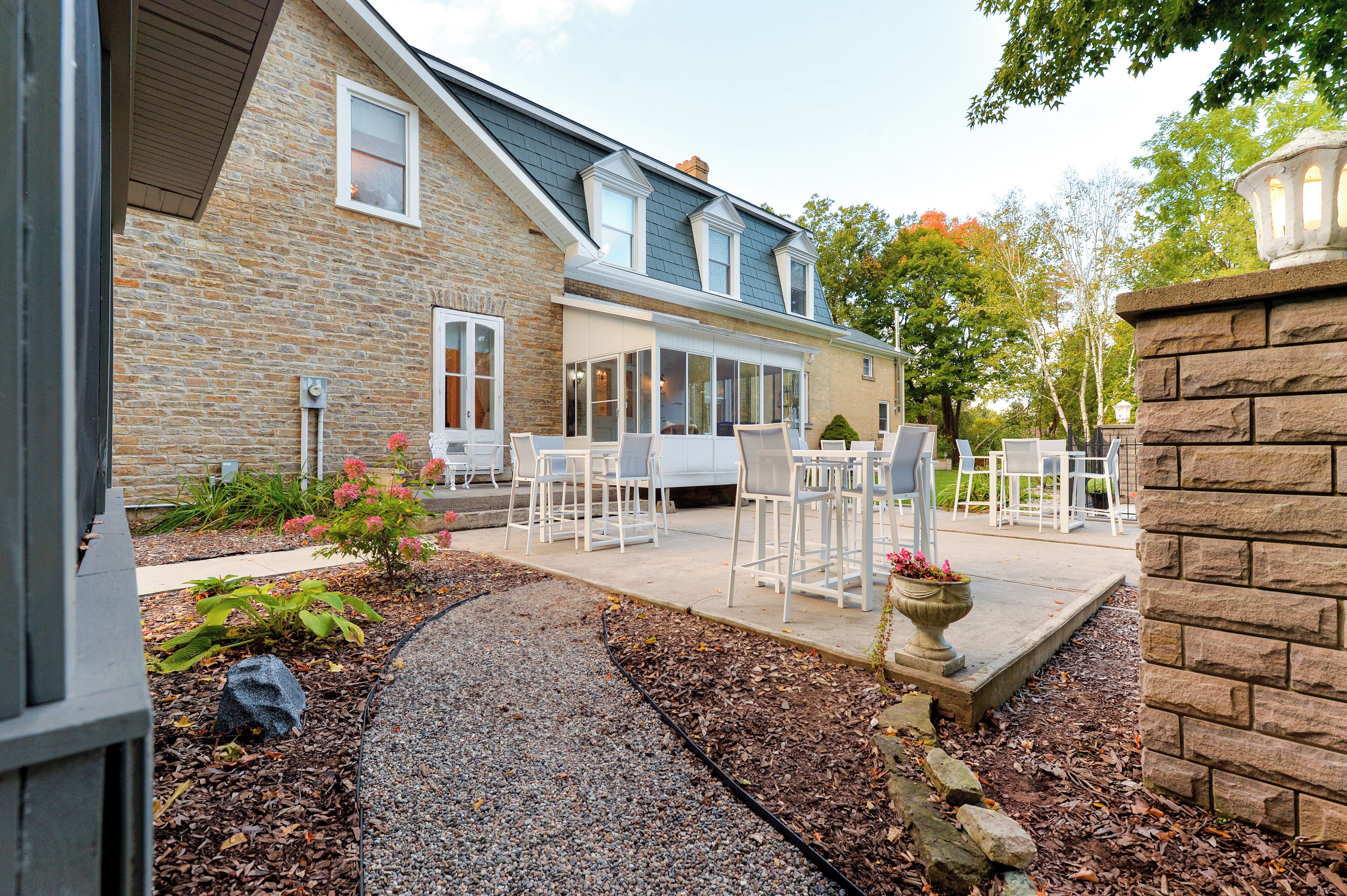 A stone building with a patio area featuring outdoor seating and a stone planter.